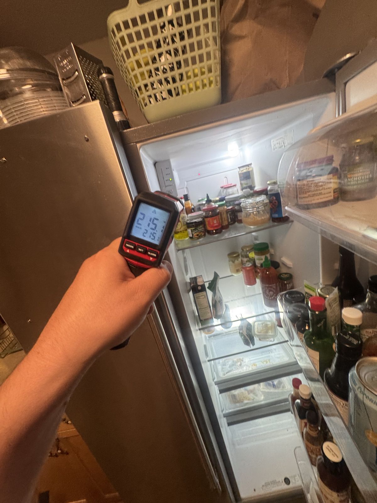Technician checking refrigerator temperature with an infrared thermometer